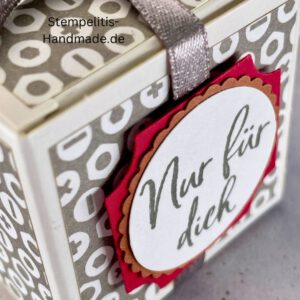 handdekorierte Geschenkschachtel mit Aufschrift „Nur für dich“, Geschenkschachtel mit grauem Muster und rotem Etikett, kleine Geschenkbox mit Satinband, Vorderansicht der Schachtel „Nur für dich“, offene Geschenkbox mit Inhalt, Detailaufnahme Schriftzug „Nur für dich“, stilvolle Geschenkverpackung mit Band